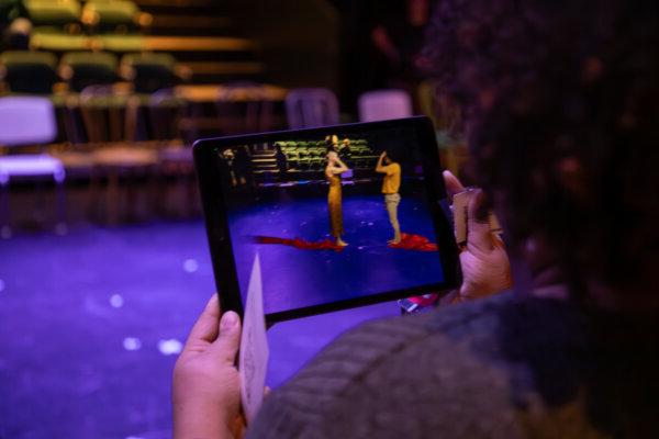 An audience members uses an iPad to watch virtual dancers perform on-stage in Glaize Studio 剧院